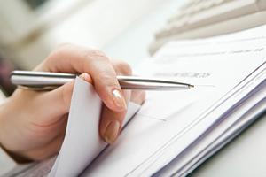 hand holding pen over paperwork