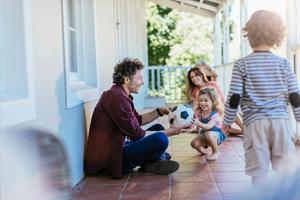 man, woman and two young kids with soccer ball on a front porch