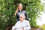 Young woman is visiting her grandmother in nursing home having a walk with here in a wheelchair
