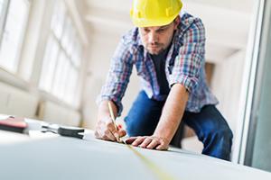 renovation contractor measuring a board