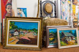 Collection of gold-framed oil paintings leaning against a velvet chair