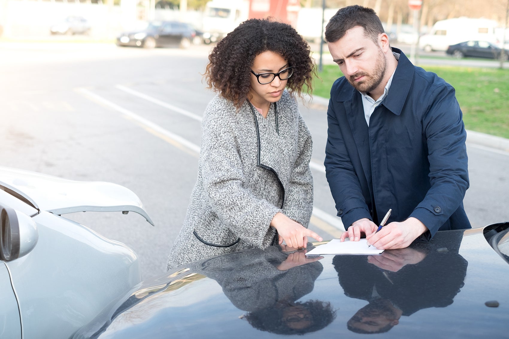 Man and woman exchanging insurance in front of car