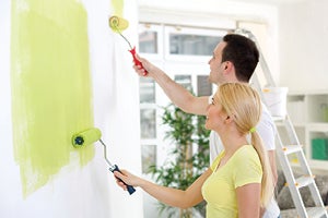 Young couple painting wall within home