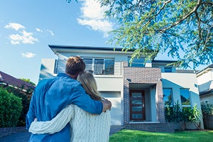 Couple standing and hugging in front of home