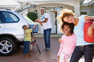 Family in front of home loading car for trip