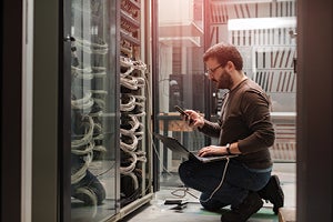 Man within computer server room conducting tests