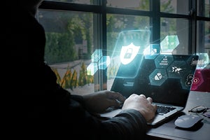 Person at computer with cyber security graphics floating in front of screen