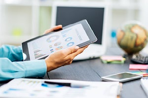 man holding tablet or ipad with the screen depicting circular and bar graphs 