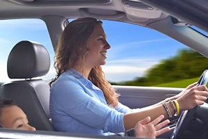 A mom driving a car with child in front seat