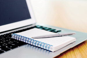 notebook and pen resting on an open laptop