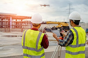 two construction workers operating a drone on site