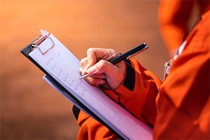 person writing notes on a clipboard