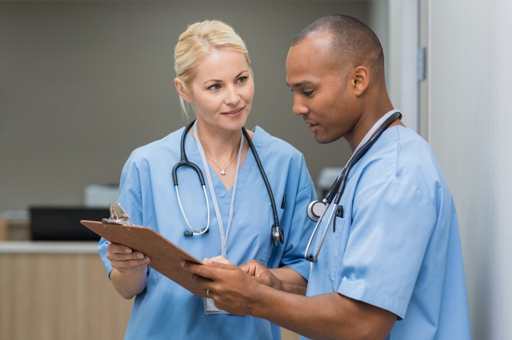 male and female nurse looking at a clipboard wearing scrubs