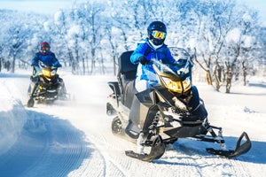 Snowmobilers riding through an open trail