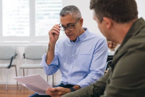 Two people sitting together and reviewing a sheet of paper