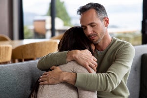 Two people sitting on a couch, embracing each other 