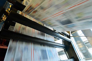 High‑speed printing press moving printed materials through rollers