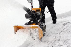 man snowblowing the sidewalk