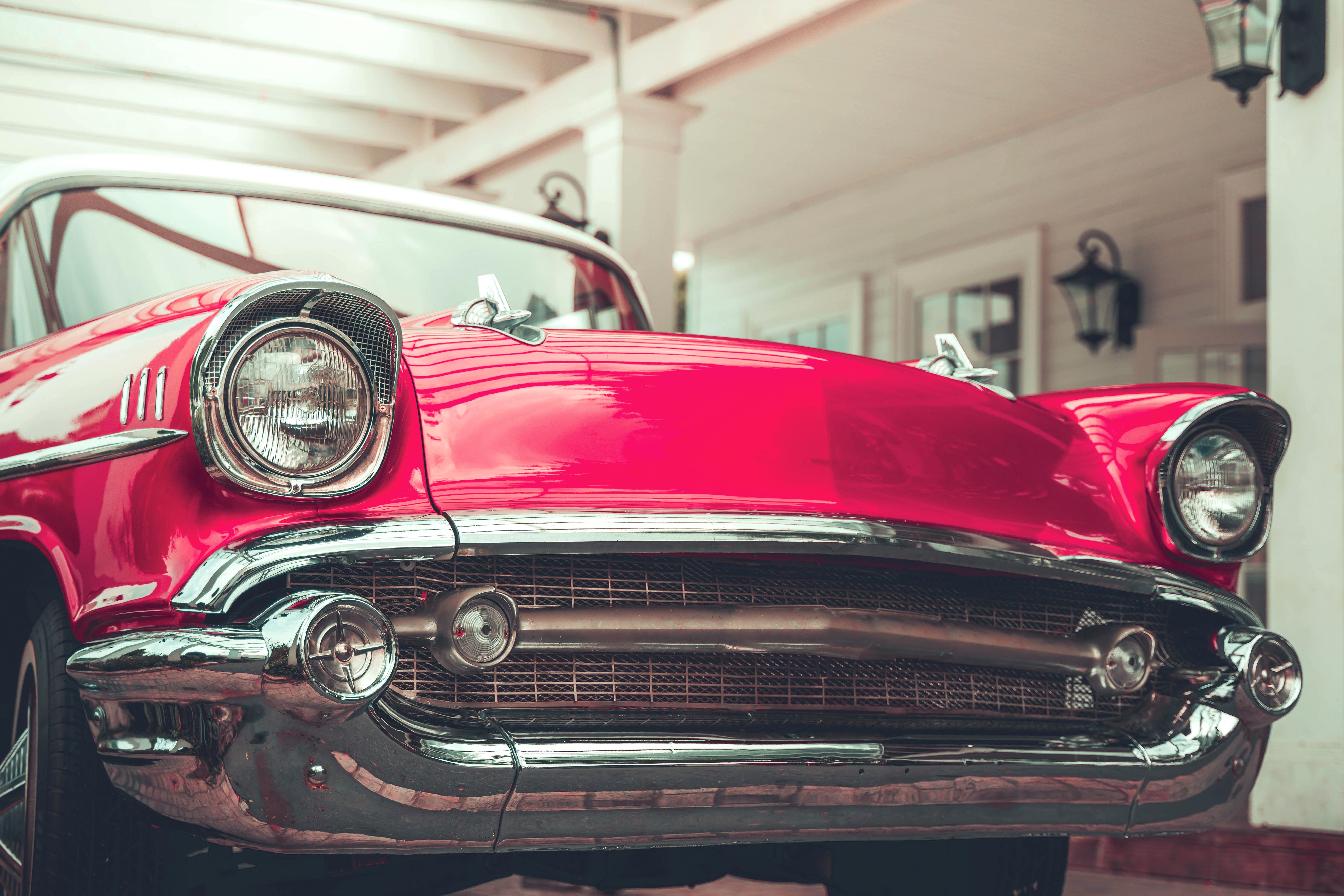 Close up of a red vintage car parked outside a house