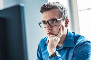 Man with glasses working at a desktop computer