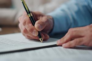 Hand holding pen, signing a document