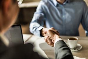 Two people shaking hands at a coffee table
