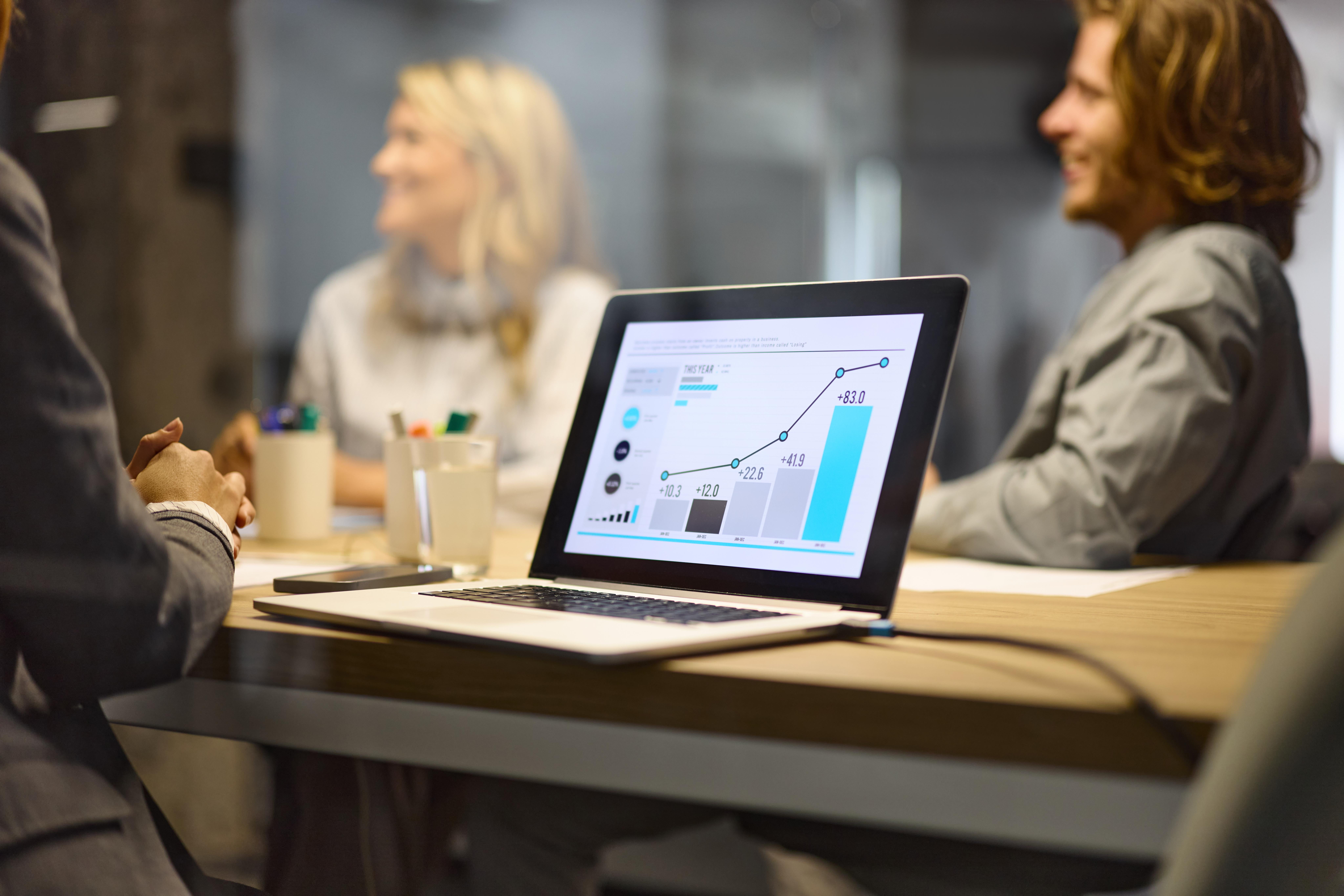 Business people sitting around at meeting with computer in foreground