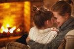 Image of mother and daughter snuggled up by a fireplace