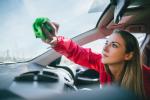 Woman cleans the inside of her car’s windshield