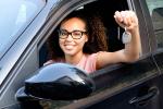 happy young woman seated in car holding car keys