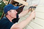 Building contractor hammering siding onto a home