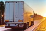 Semi-truck (cargo container) on a road in the evening while the sun sets