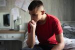 teen boy sitting on bed thinking