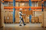 Warehouse worker wearing exoskeleton technology carrying a pallet of boxes