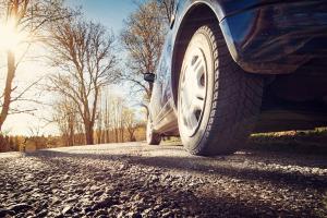 A ground-level, back tire view of car on a country road