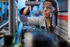 Female engineer examining machine part on a production line