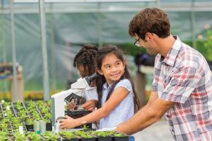 Student smiling at teacher in greenhouse