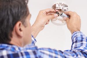 man changing battery in fire alarm