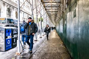Pedestrians walk under scaffolding on a city street
