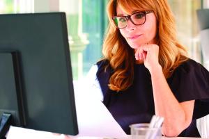 Woman, smiling, working at a desktop computer
